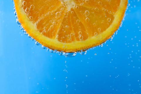 Fresh orange slice in sparkling blue water